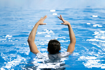 a synchronized swimming sportswoman practice new moves in the water of swimming pool alone