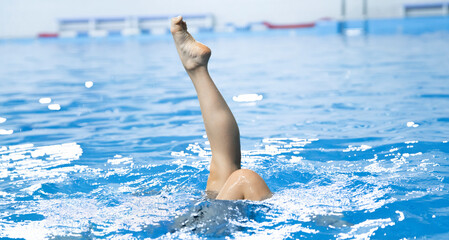 a synchronized swimming sportswoman practice new moves in the water of swimming pool alone