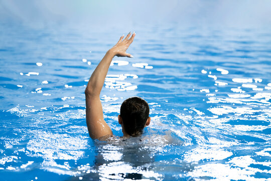 a synchronized swimming sportswoman practice new moves in the water of swimming pool alone