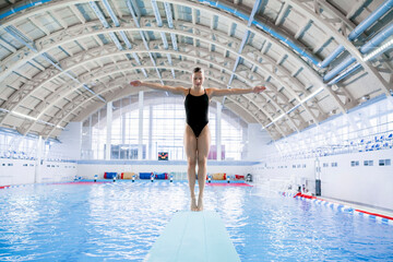 female athlete stands on a springboard, diving competition