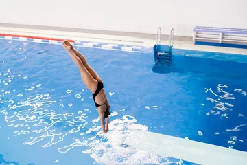 Fotobehang sportswoman in black suite dive into the swimming pool © Mihail