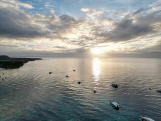 Fototapeta na wymiar Aerial view of a fleet of sailboats drifting in sea at sunset in Panglao, Philippines