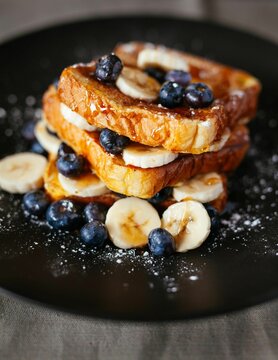 Close-up image of a golden-brown waffle topped with fresh blueberries and sliced bananas