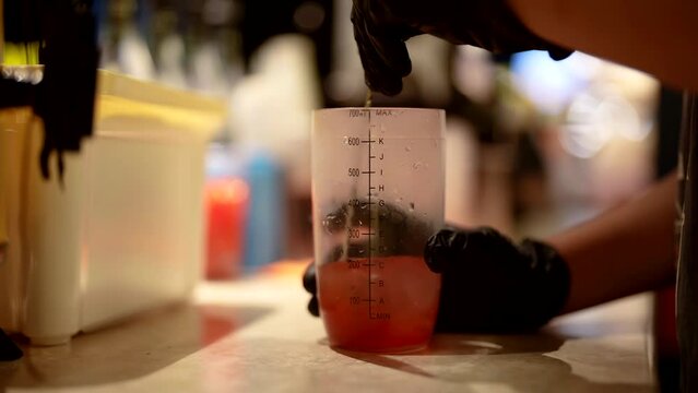 professional bartender stirring ingredients for cocktail and ice in measuring cup, closeup view