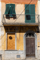 House exterior and entrance in Pisa, Italy. Derelict condition with plaster coming off and boarded up window