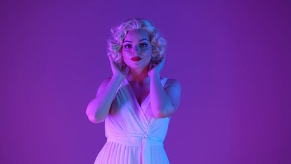 Portrait of a charming woman in the image of close up. Woman with bright makeup in white dress and wig in studio in pink and green neon light.