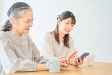 スマートフォンを操作するシニア女性と若い女性