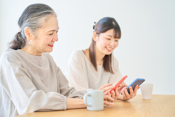 スマートフォンを操作するシニア女性と若い女性