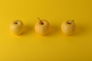 Trio of apples arranged in a visually appealing composition on yellow background