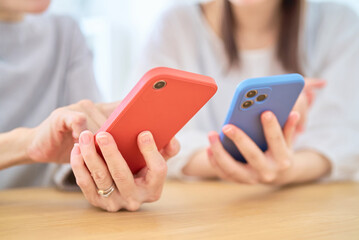 スマートフォンを操作する女性たちの手元