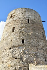 Fototapeta na wymiar Stone tower of an ancient fortress against a blue sky