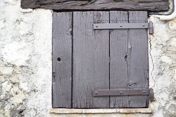 Antique window with weathered wood shutters in a historic stone structure