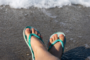 Blue colored summer shoe sandals female woman barefoot on sea shore beach as vacation tourism and...