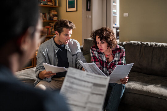 Young Couple Talking To Their Financial Advisor In The Living Room Of Their Home