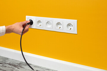 Man plugging cord into a electrical outlet.