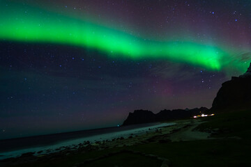 Awesome Northern lights over the beach, reflection in the silky water. Lofoten islands, Norway.