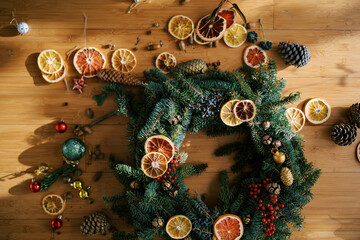 Pieces of dried oranges, toys and fir cones lie near the Christmas wreath on the floor