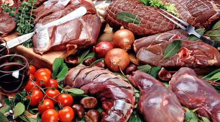 A Large Composition of hunting raw meats with decorative elements such as vegetables and herbs.