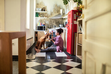 Young woman feeding dog for its birthday in the kitchen