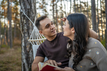 Man and woman young adult couple in nature hold and read book in love