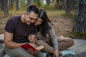 Man and woman young adult couple in nature hold and read book in love
