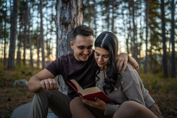 Man and woman young adult couple in nature hold and read book in love