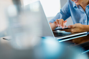 Woman using the smartphone at the laptop