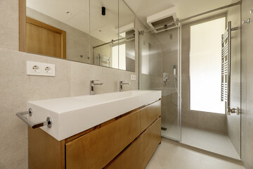Beautiful modern bathroom with gray stone-like tiles, large mirror in the wall cabinet, towel...
