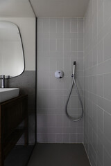 Small modern bathroom with gray stone effect tiles, mirror on the wall, shower cubicle with glass...