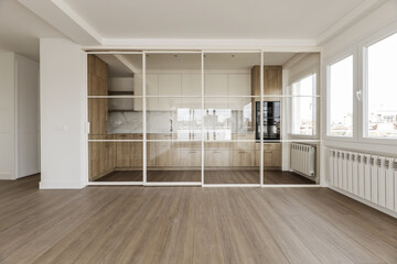 Frontal image of a modern design kitchen with wooden furniture and retractable glass and white metal screen