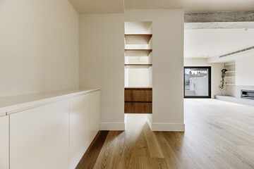 Fototapeta premium empty living room with custom wooden shelves between a pillar and the wall in a living room with wooden floors