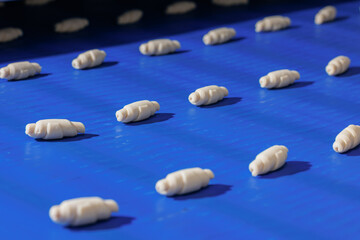 Concept smart modern technology in food industry. Process Production of French croissants, puff pastry dough pieces are automatically moved along line conveyor