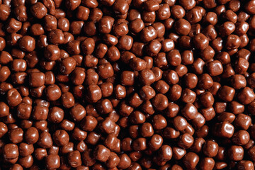Closeup brown dragee, chocolate covered nuts, sweet candy background