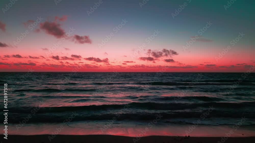 Sticker Beautiful scene of sea tide waves with red sunset cloudy sky on the horizon