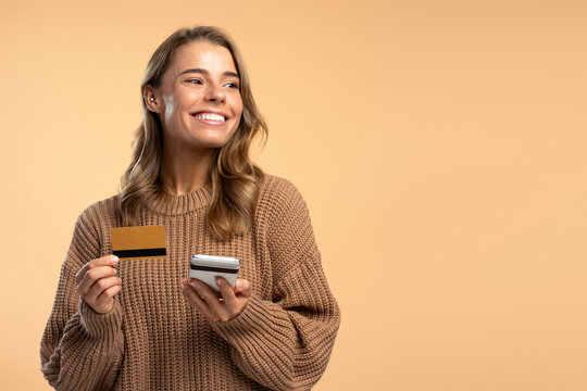 Portrait beautiful smiling woman holding mobile phone, credit card shopping online with sales isolated on background, copy space. Internet store, electronic money concept
