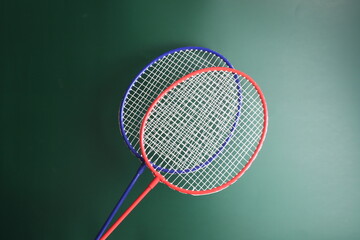 Two badminton racers in a dark green background 