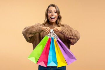 Young beautiful excited woman wearing holding colorful shopping bags looking at camera isolated on  background. Shopping, black Friday, sale, advertisement concept - obrazy, fototapety, plakaty
