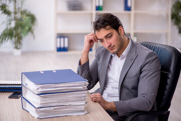 Naklejka premium Young male employee and too much work in the office
