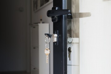 Keys hanging from the lock of an open house door. Home security, real estate concept.