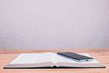 An open Holy Bible on the table. Phone on the Bible. Reading God's Word.