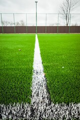 Vertical shot of a white line painted on an artificial green soccer field