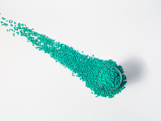Turquoise masterbatch granules of cold cut type, placed in a glass cup on a white background, this...