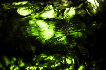 Tektite glass green texture. Moldavite gemstone close up. Flow patterns of natural glass.