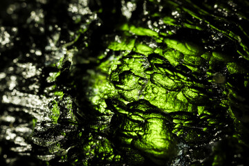 Tektite glass green texture. Moldavite gemstone close up. Rough surface.