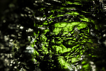 Tektite glass green texture. Moldavite gemstone close up. Rough surface. © Petr