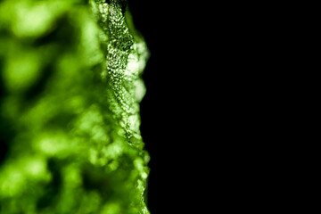 Tektite glass green texture. Moldavite gemstone close up. Rough surface.