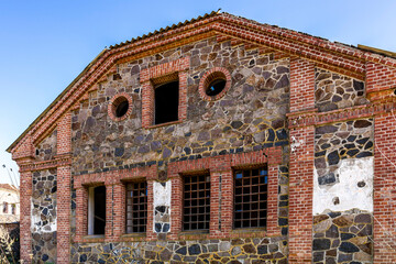 Old building, mill. Stone, brick. Broken windows, sunny day.