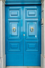 a blue double door leading into a brick building with decorative knock