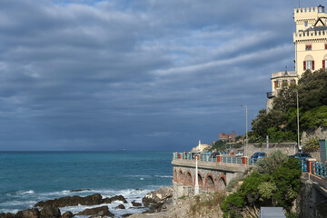 Scenic Mediterranean riviera coast in Liguria. Genoa Quarto dei Mille with Boccadasse village in the background. In foreground a  with a stretch of the Aurelian state road.