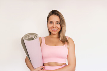 Young caucasian cheerful smiling fit athlete blonde woman in pink gym outfit holding yoga mat in...